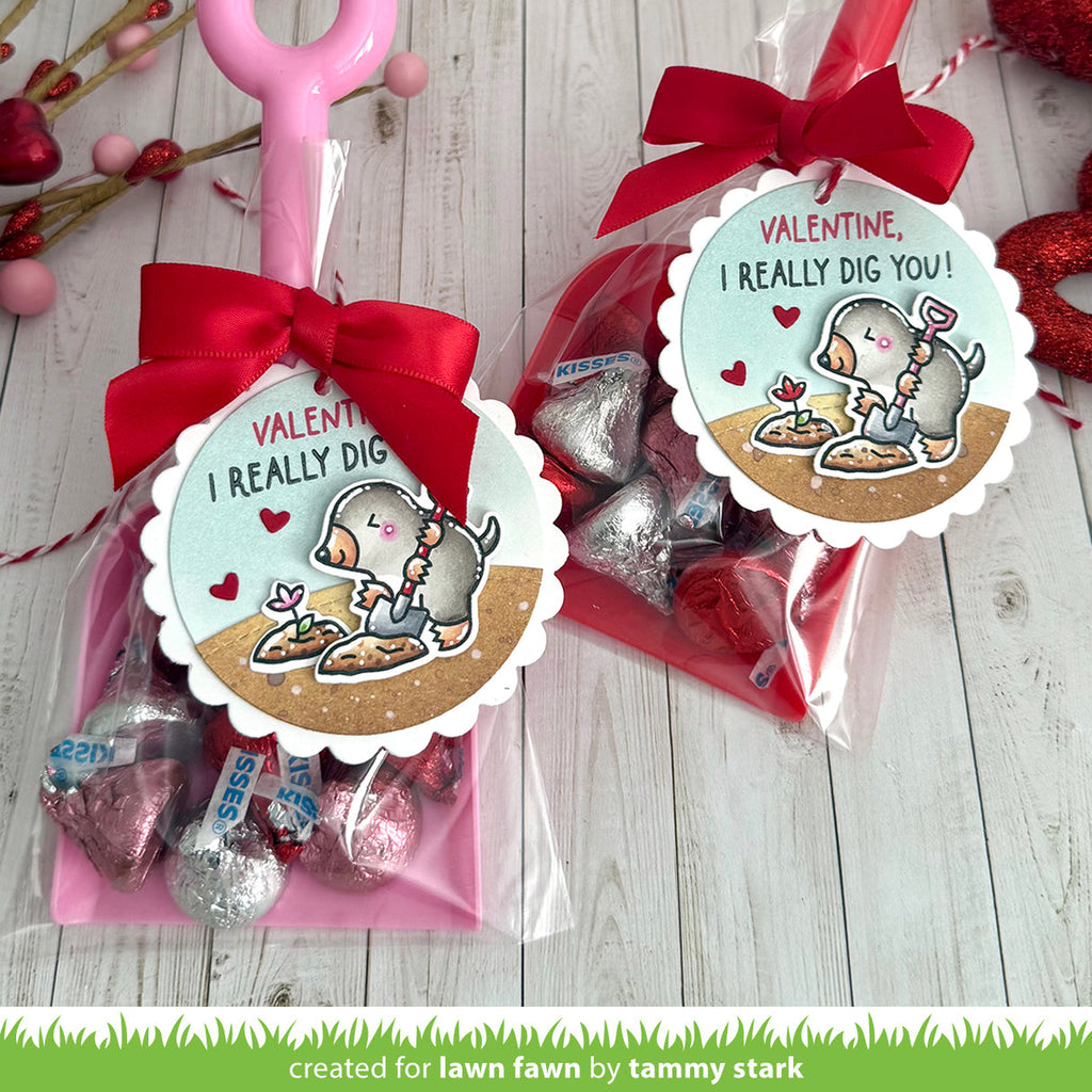 Two Valentine's Day gift bags with cartoon characters and decorative ribbons on a wooden surface.