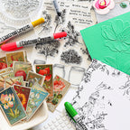 A flat-lay arrangement of distress crayons, clear stamp sheets with botanical and floral line art, vintage-style floral sticker cards, and a green embossed card on a white surface.