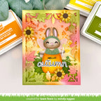 Autumn-themed card with a rabbit in an orange outfit and sunflowers, surrounded by stamping supplies. | color-code:alt1