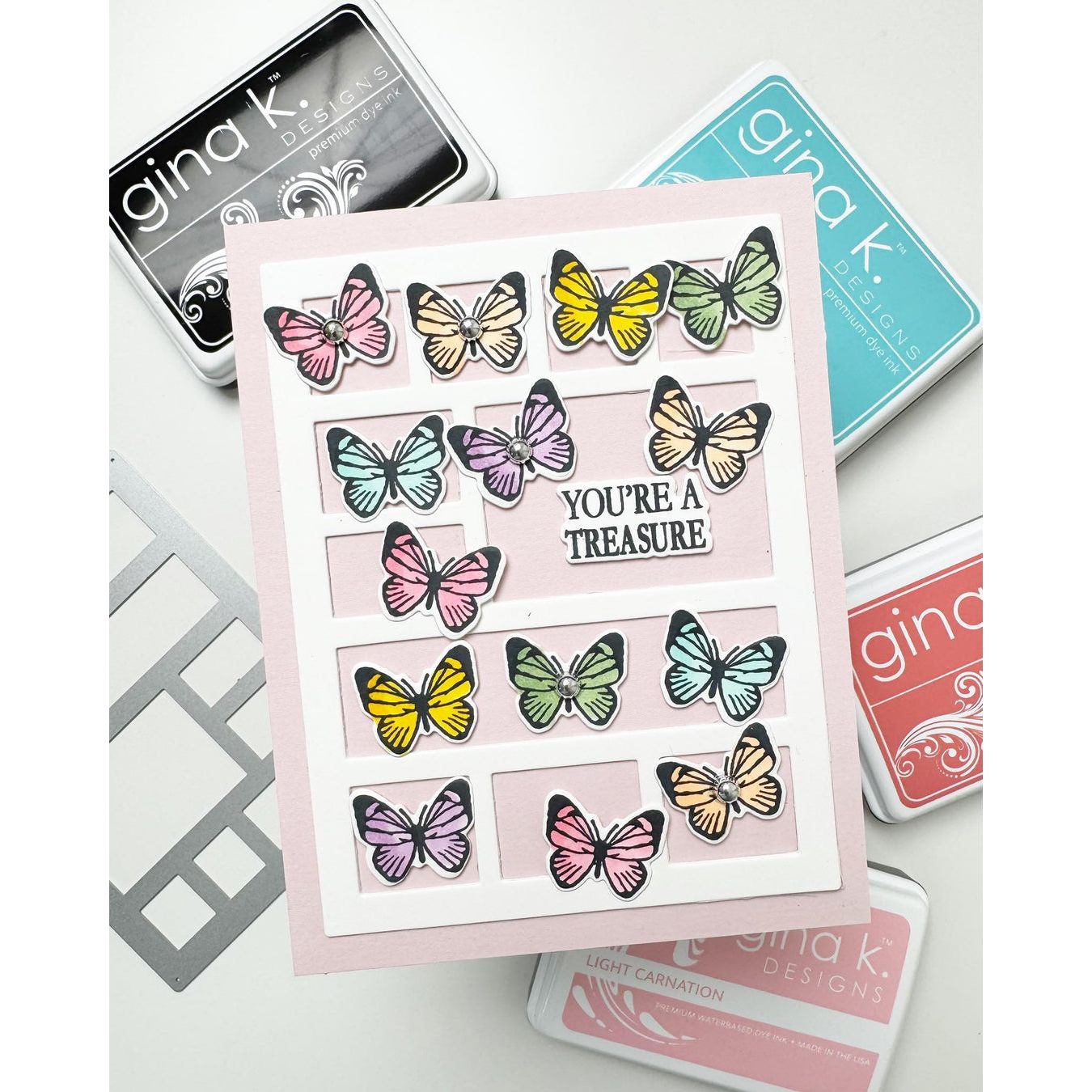 Card with colorful butterfly designs and 'You're a Treasure' text, surrounded by Gina K. Designs stamps on a light background.