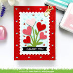 Valentine's Day card with heart design and 'I HEART YOU' text on a red border, surrounded by crafting supplies.