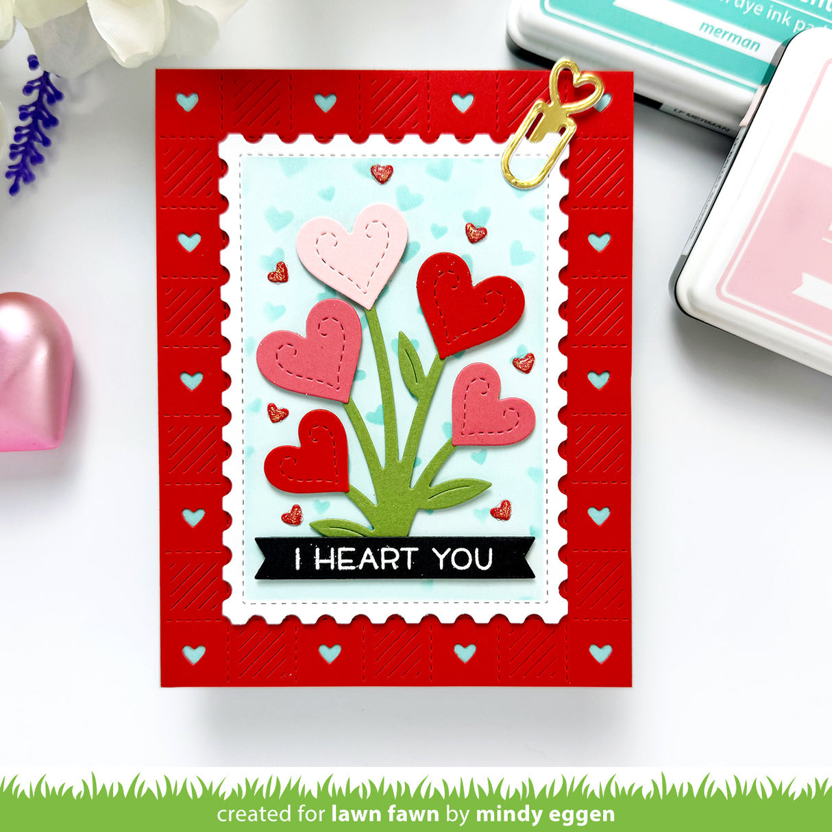 Valentine's Day card with heart design and 'I HEART YOU' text on a red border, surrounded by crafting supplies.
