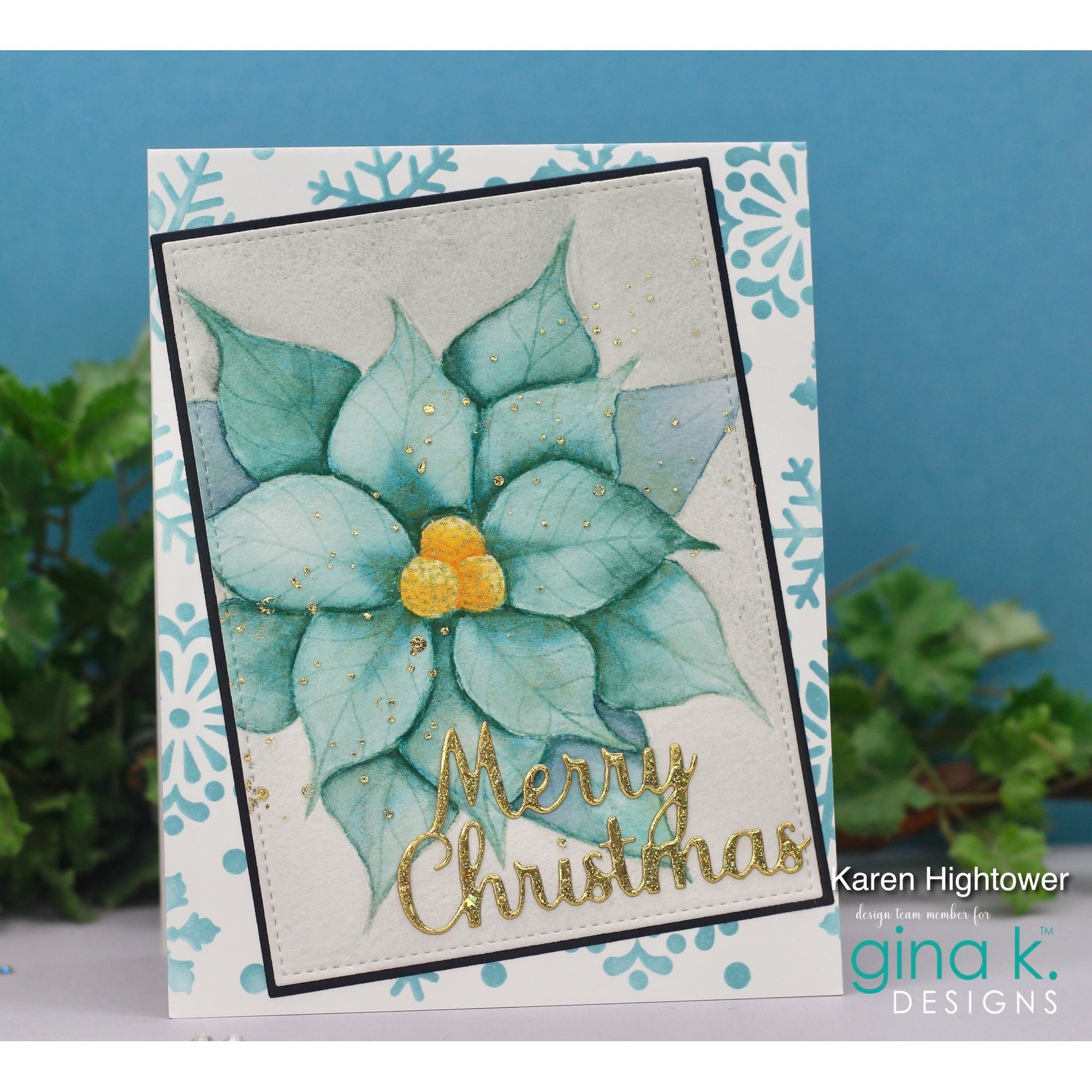 Christmas card with teal poinsettia and 'Merry Christmas' text on a decorative background, featuring the brand 'gina k. Designs'.