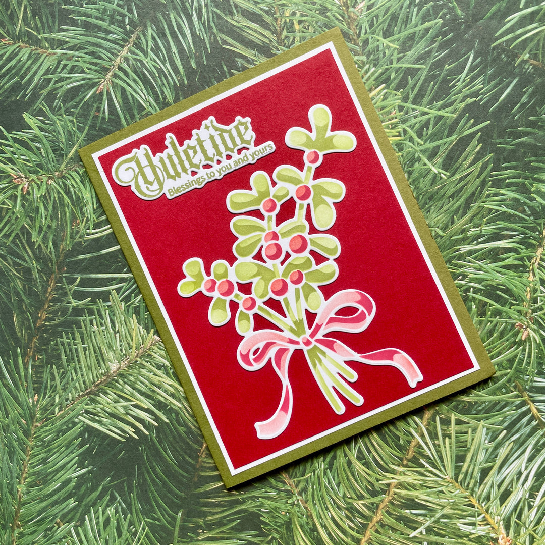 Christmas card with holly design and 'Mistletoe' text on a green leaf background
